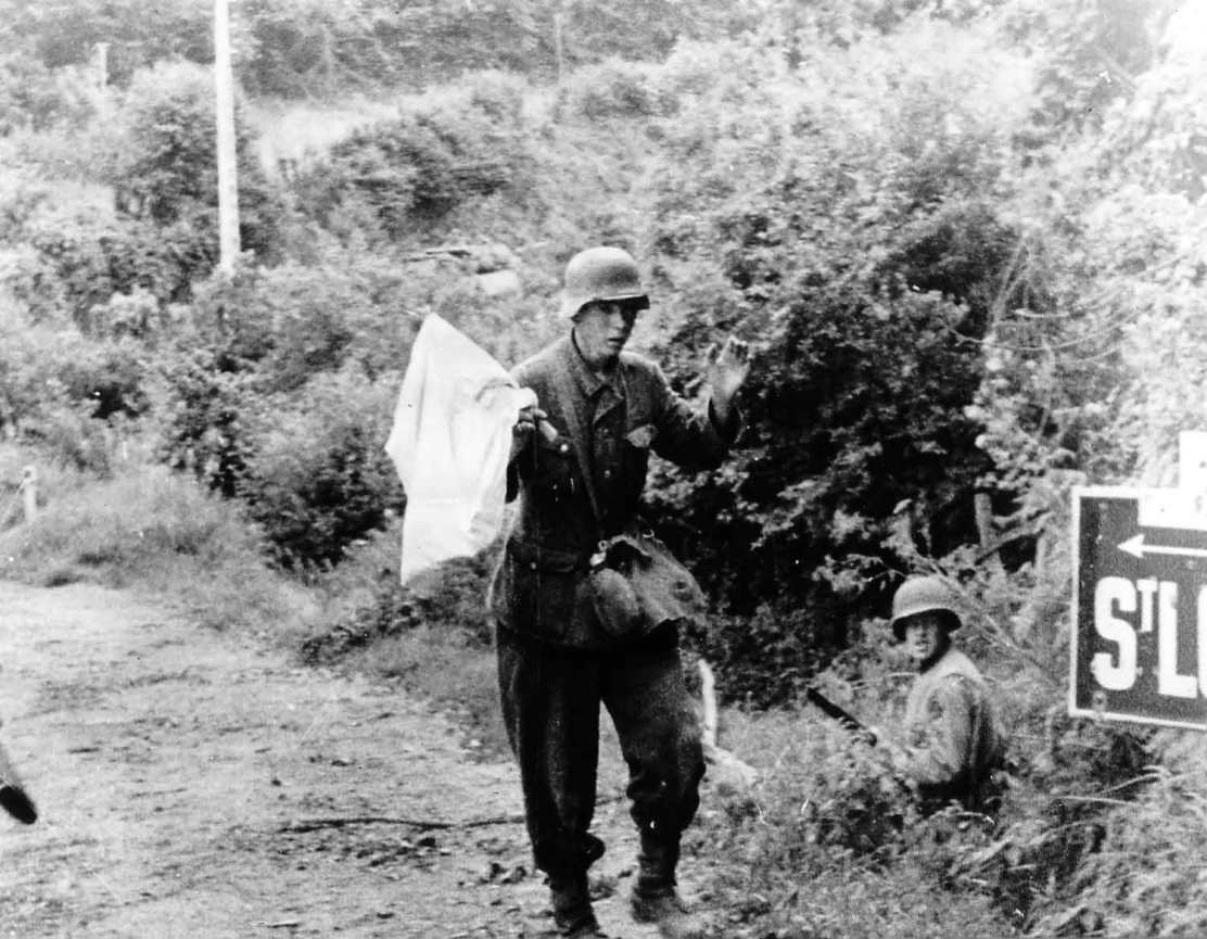 Le 18 juillet 1944, un jeune soldat allemand se constitue prisonnier tout prÍt de Saint LÙ avec un drapeau blanc rapidement confectionnÈ. SÈquence filmÈe, visible ici: http://www.flickr.com/photos/mlq/6334351670/ Ce panneau largement photographiÈ est ‡ 700 mËtres des premiËres maisons de Saint-LÙ, sur GC 6 (aujourd'hui D6) venant d'Isigny sur Mer. La Task Force Cota le 18 juillet 1944, sa composition (ÈlÈments de la 29th US ID.) : Brig. Gen. Norman D. Cota, commandant en second de la division Ce groupement tactique se compose des unitÈs suivantes : -29th Cavalry Reconnaissance Troop (moins des ÈlÈments), ‡ bord de vÈhicules blindÈs M8 visibles en p011508. -d'un Platoon de Sherman du 747th Tank Bn, -d'un Platoon de la Cannon Company (57mm AT Gun) du 175th Infantry Regt, -d'une section de l'Antitank Company du 175th IR, -d'un dÈtachement du 29th Military Police Platoon, -d'une section du 121 st Engineer Combat Bn, -d'une Recce Platoon du 821st Tank Destroyer Bn (Towed), -de la compagnie B (douze TD M10) du 803rd Tank Destroyer Bn (SP), -d'un dÈtachement des Civils Affairs, -de deux groupes d'observateurs d'artillerie, l'un du 227th Field Artillery Battalion, l'autre du quartier gÈnÈral de l'artillerie divisionnaire. En tout 600 hommes qui se dÈplacent avec en tÍte un Sherman Flail (engin de dÈminage) voir la p011437 mÍme lieu en amont du poteau indicateur.