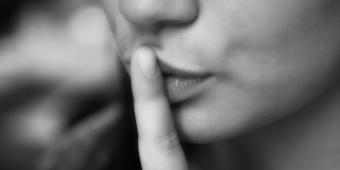 Mouth of girl who asks for silence with gesture