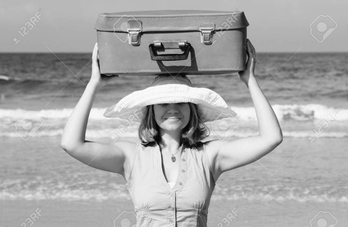 17081747-young-woman-standing-on-the-beach-with-vintage-suitcase